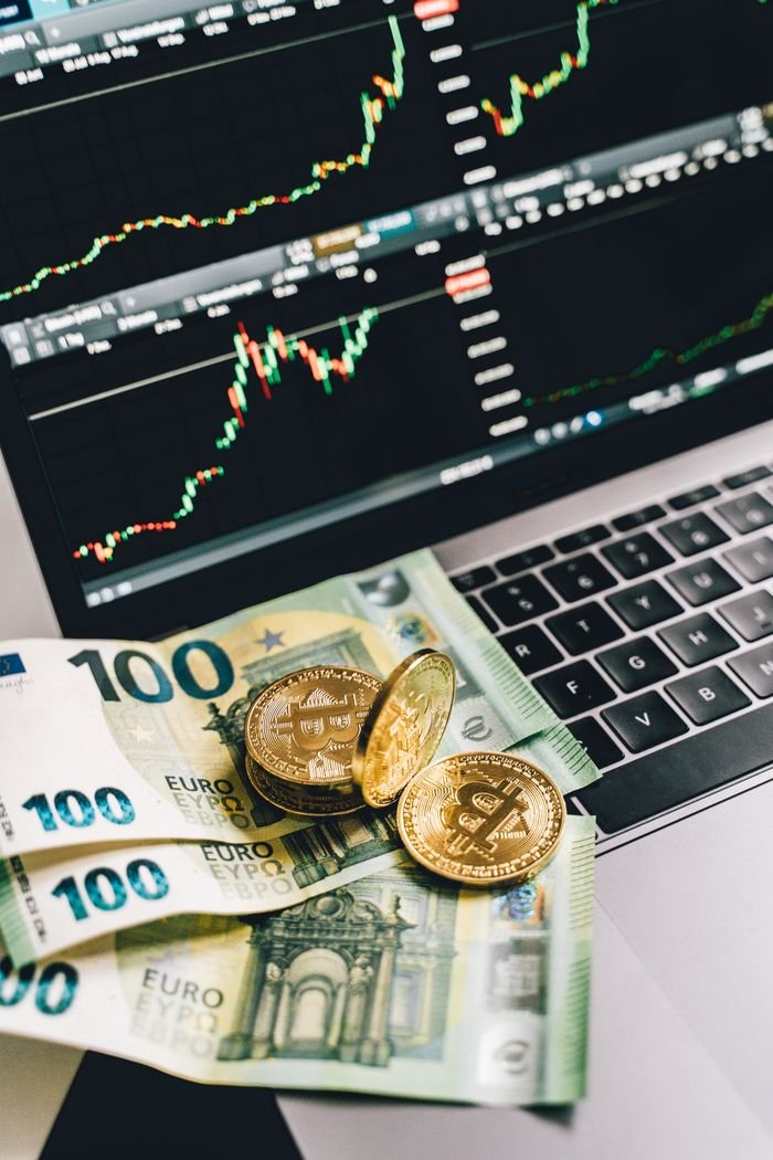 Bitcoin and Euro notes on laptop keyboard with stock market graphs in Berlin, Germany.